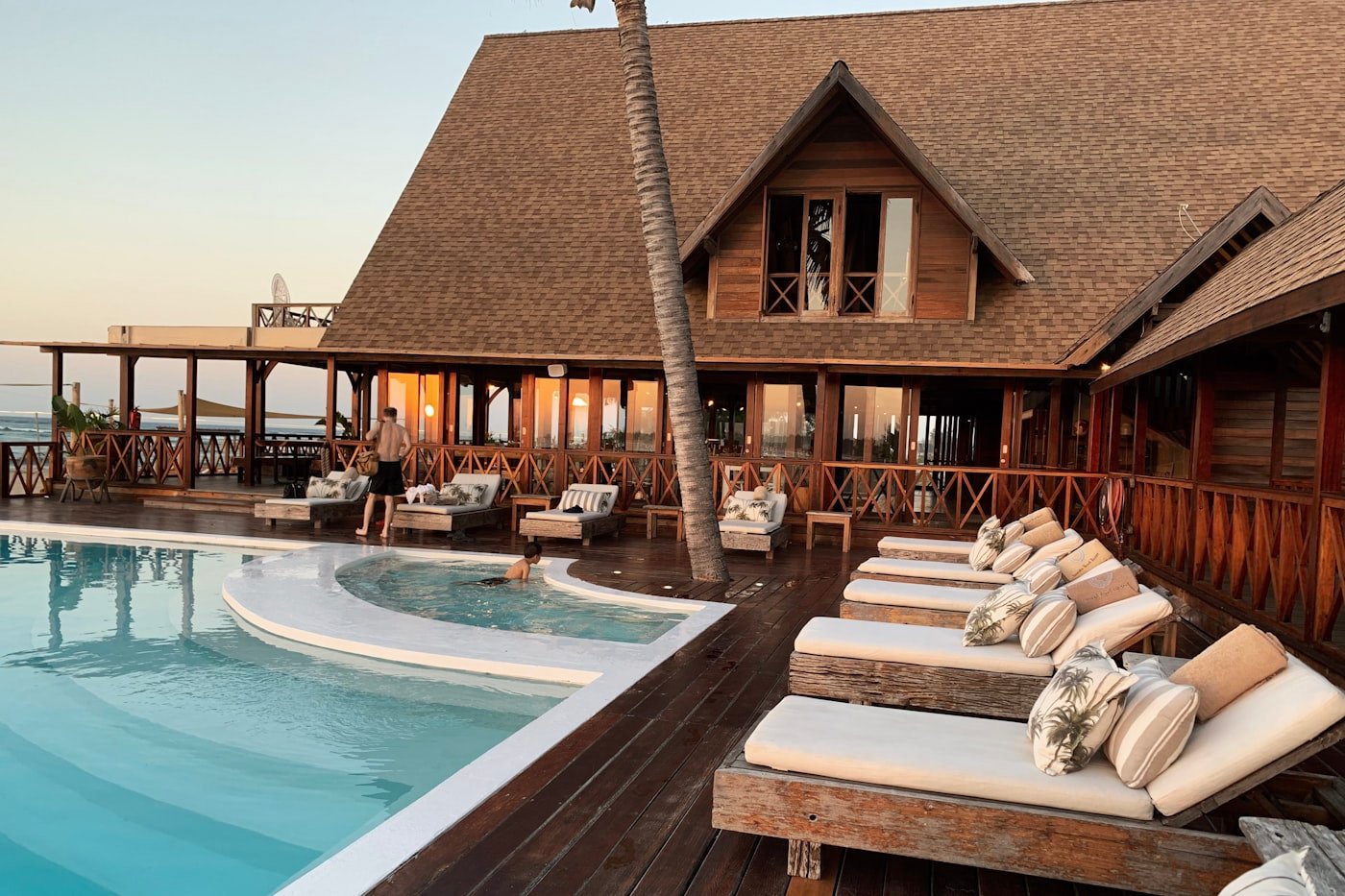 A beachfront luxury villa with a private pool and sun loungers at dusk