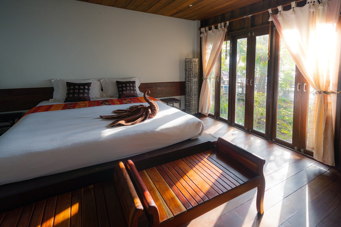A warm, light-filled hotel guest room with garden views